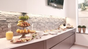 Una cocina moderna con salpicadero de piedra, una exhibición de frutas y un televisor de pantalla plana montado en la pared.