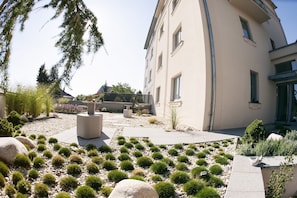 A landscaped garden with a variety of plants and a modern building with large windows. - Villa na Vinici (Prague)