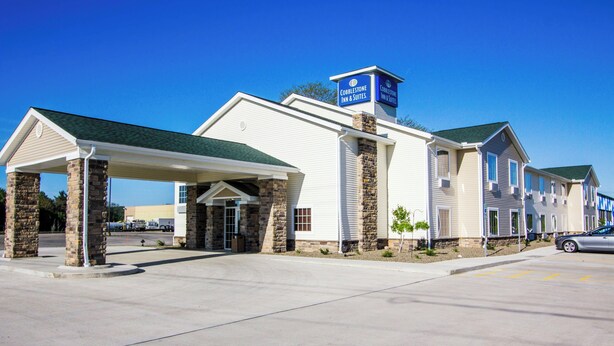 A hotel with a covered entrance, stone pillars, and a sign for Cobblestone Inn & Suites.