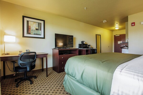 A hotel room with a bed, desk, chair, television, and a coffee maker. - Cobblestone Inn & Suites - Corry (Corry)
