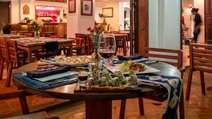 Een restaurant met ronde tafels, houten stoelen en een bar op de achtergrond.