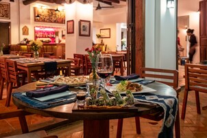 Un restaurante con mesas redondas, sillas de madera y una zona de bar al fondo.