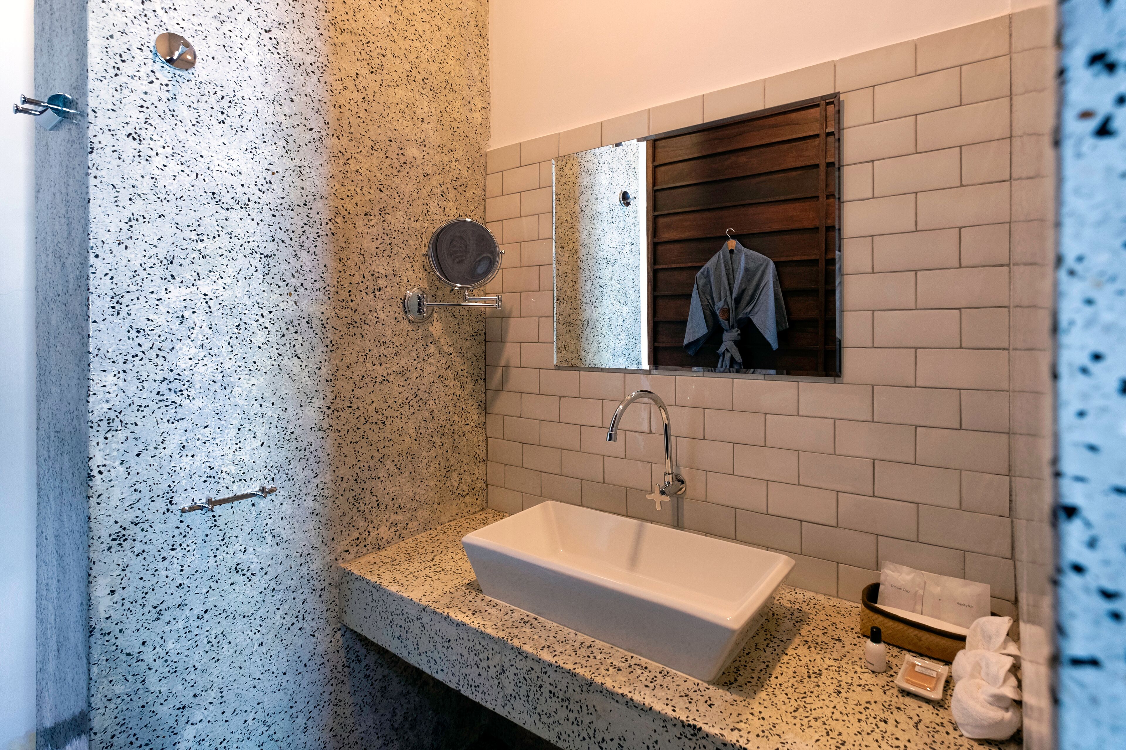 Un baño con un lavamanos rectangular, un espejo y una zona de ducha.