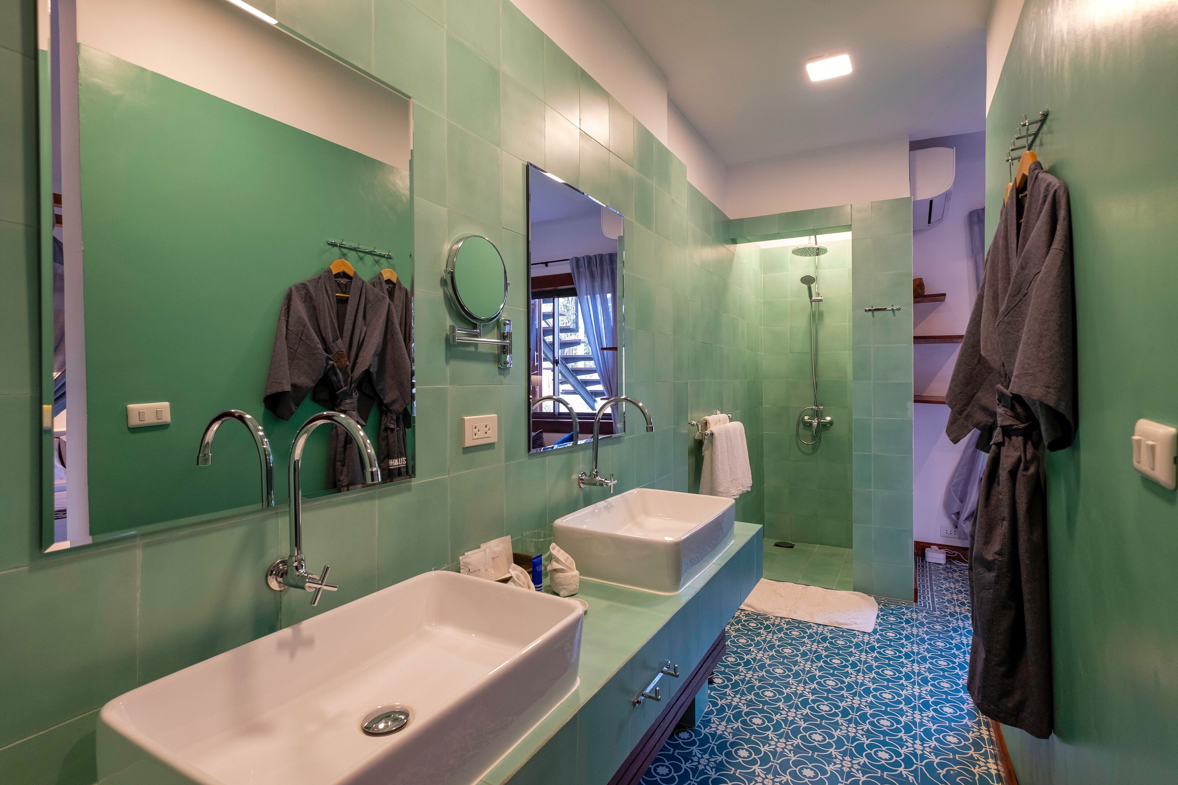 A bathroom with two sinks, a large mirror, and a shower.