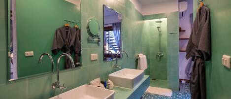 A bathroom with two sinks, a large mirror, and a shower.