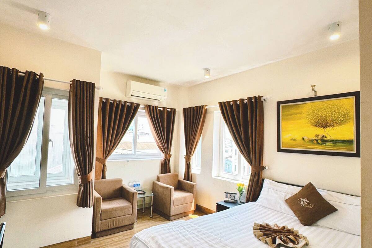 Ein Hotelzimmer mit einem großen Bett, zwei Sesseln, einem kleinen Tisch und einem Bild an der Wand.
