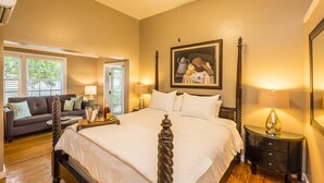 A bedroom with a large bed, a sofa, a nightstand, and a painting on the wall. - L'Habitation Guest House - Adults Only (Key West)