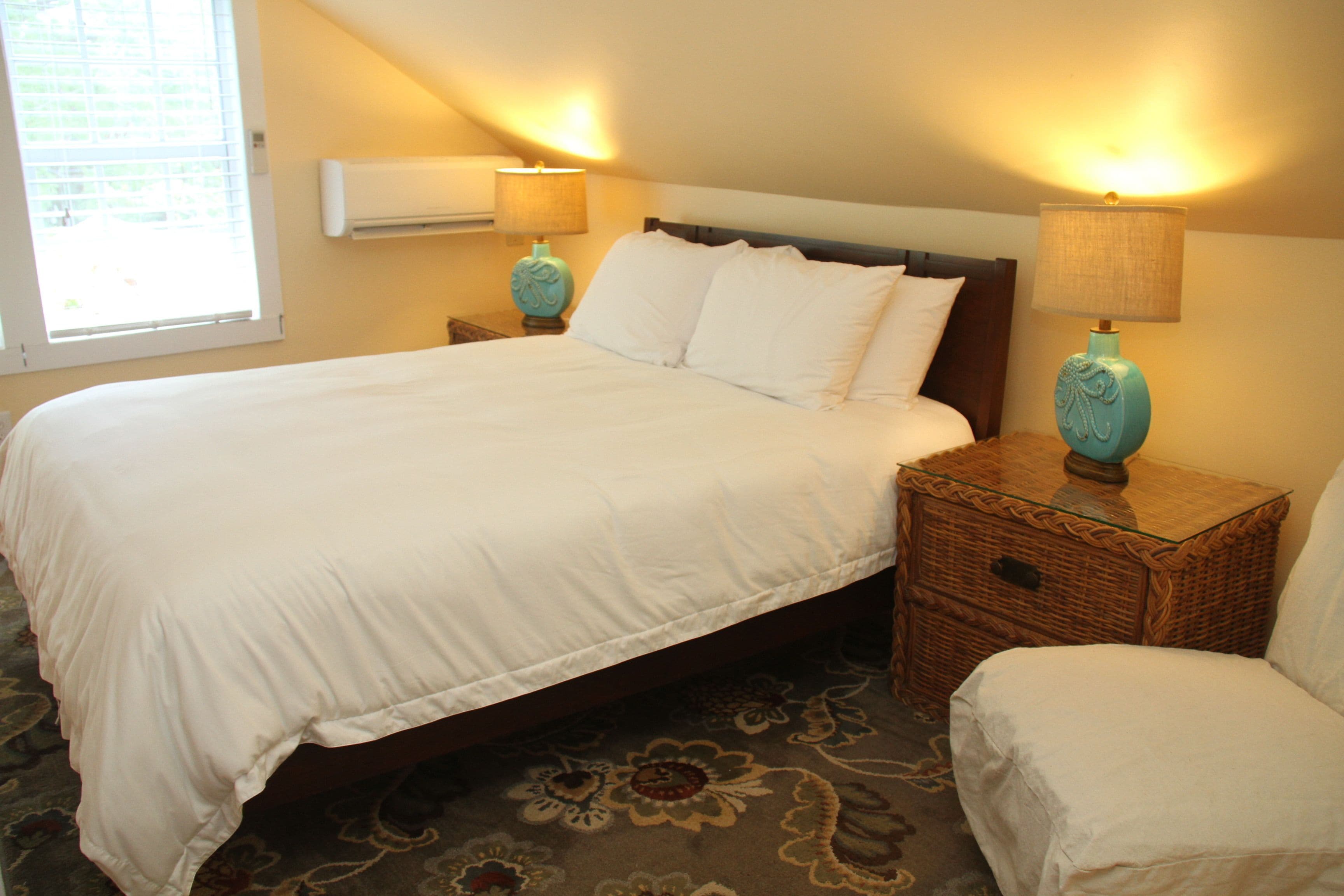 A neatly made bed with white linens, two bedside tables with lamps, and a patterned carpet.