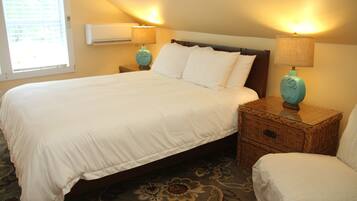 A neatly made bed with white linens, two bedside tables with lamps, and a patterned carpet.