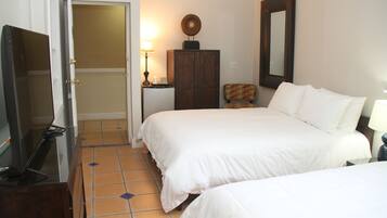 A hotel room with two beds, a wardrobe, a desk with a lamp, and a television.