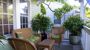 A covered porch with wicker furniture, potted plants, and a view of the house. - L'Habitation Guest House - Adults Only (Key West)