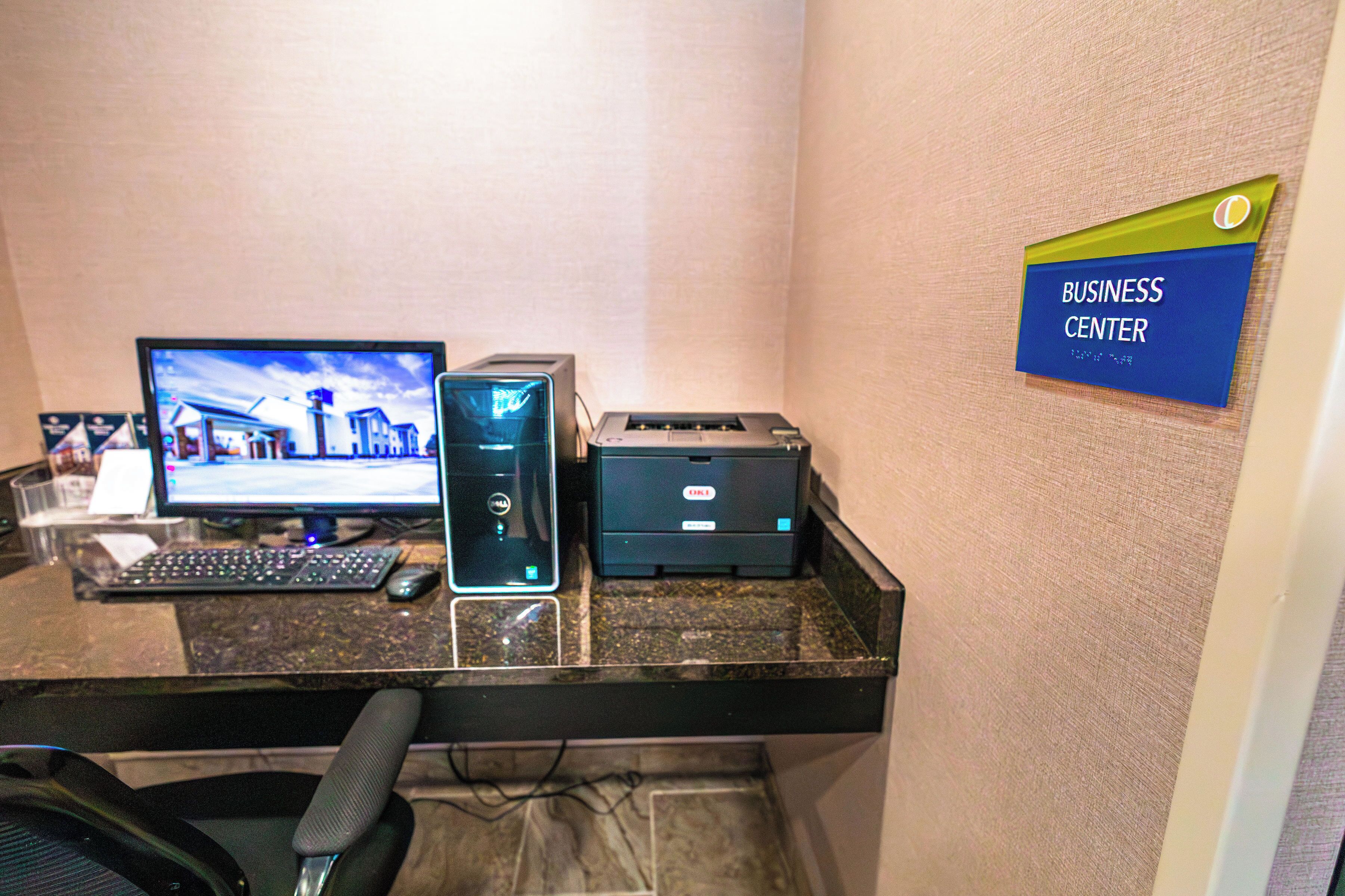A business center desk with a desktop computer, monitor, keyboard, mouse, and printer.