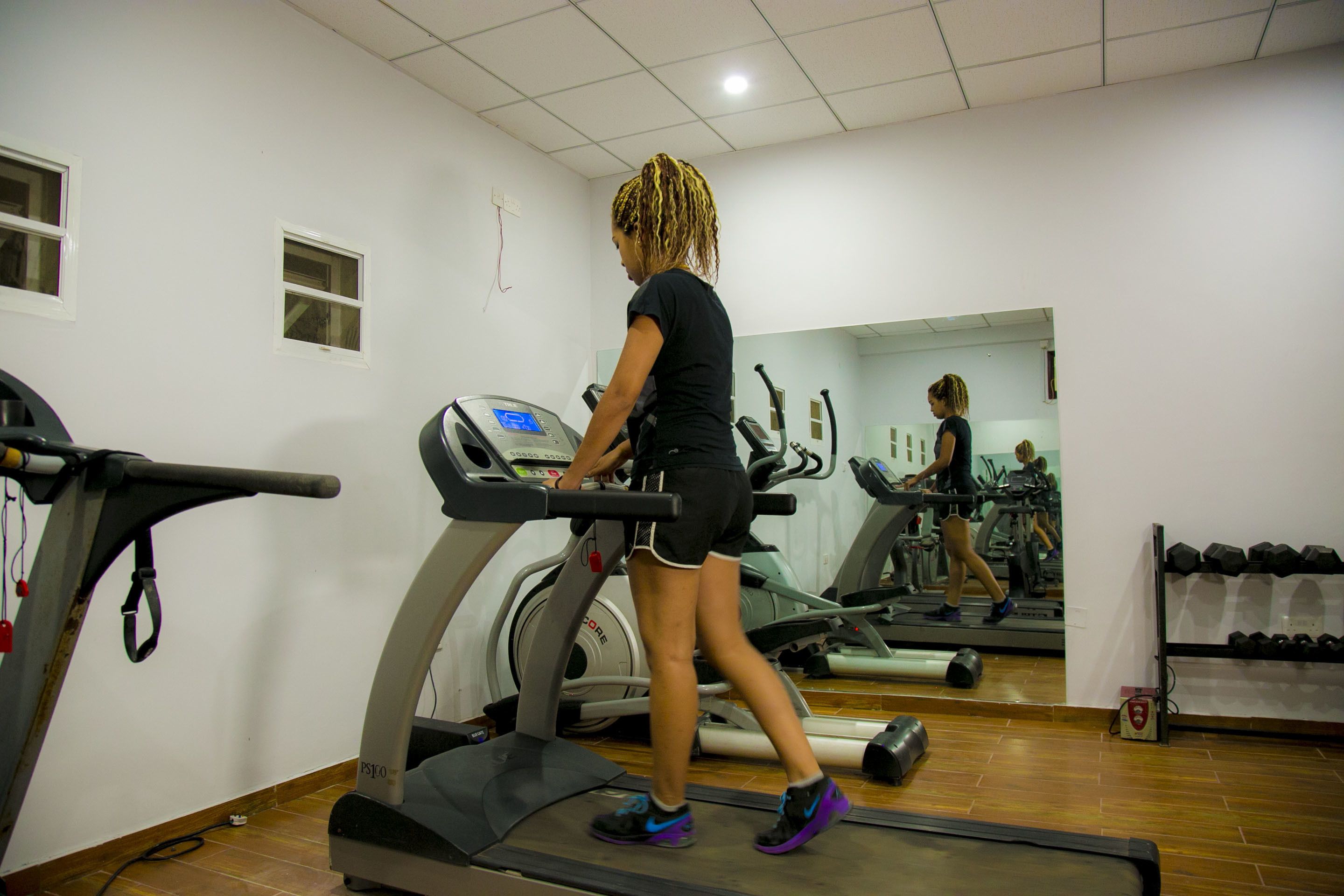 A gym with treadmills, a mirror, and a rack of dumbbells.