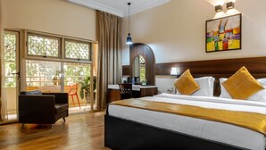 Habitación de hotel con una cama grande, un escritorio, una silla y vistas a través de un ventanal corredero.