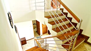 A multi-level wooden staircase with metal railings, leading to a landing with a door to a bathroom. - De Bukit Dago Villa by HouseinBandung (Bandung)