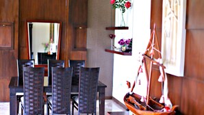A dining area with a wooden table and chairs, a decorative ship model, and a mirror on the wall. - De Bukit Dago Villa by HouseinBandung (Bandung)