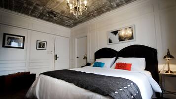 Une chambre d’hôtel avec un grand lit, un lustre et des tableaux encadrés accrochés au mur.