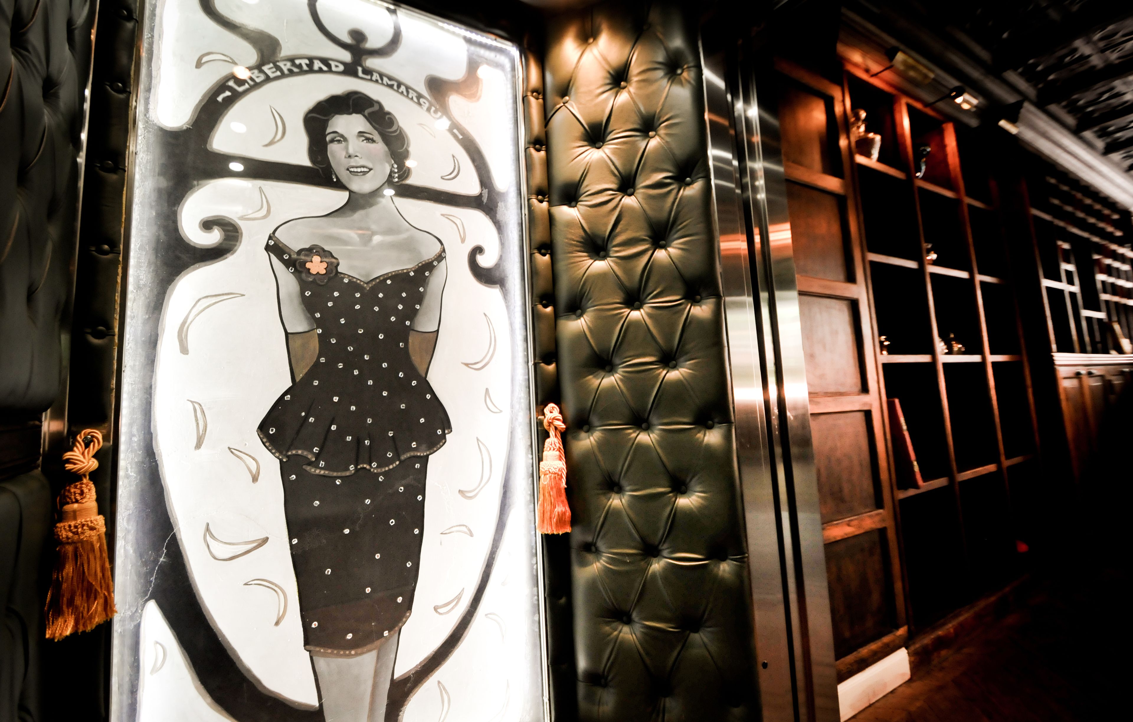 A poster with a woman in a polka dot dress and a tufted leather wall.