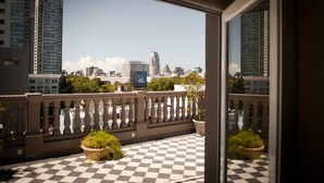 A balcony with a checkered floor, potted plants, and a view of a cityscape with tall buildings. - Hotel Clasico (Buenos Aires)