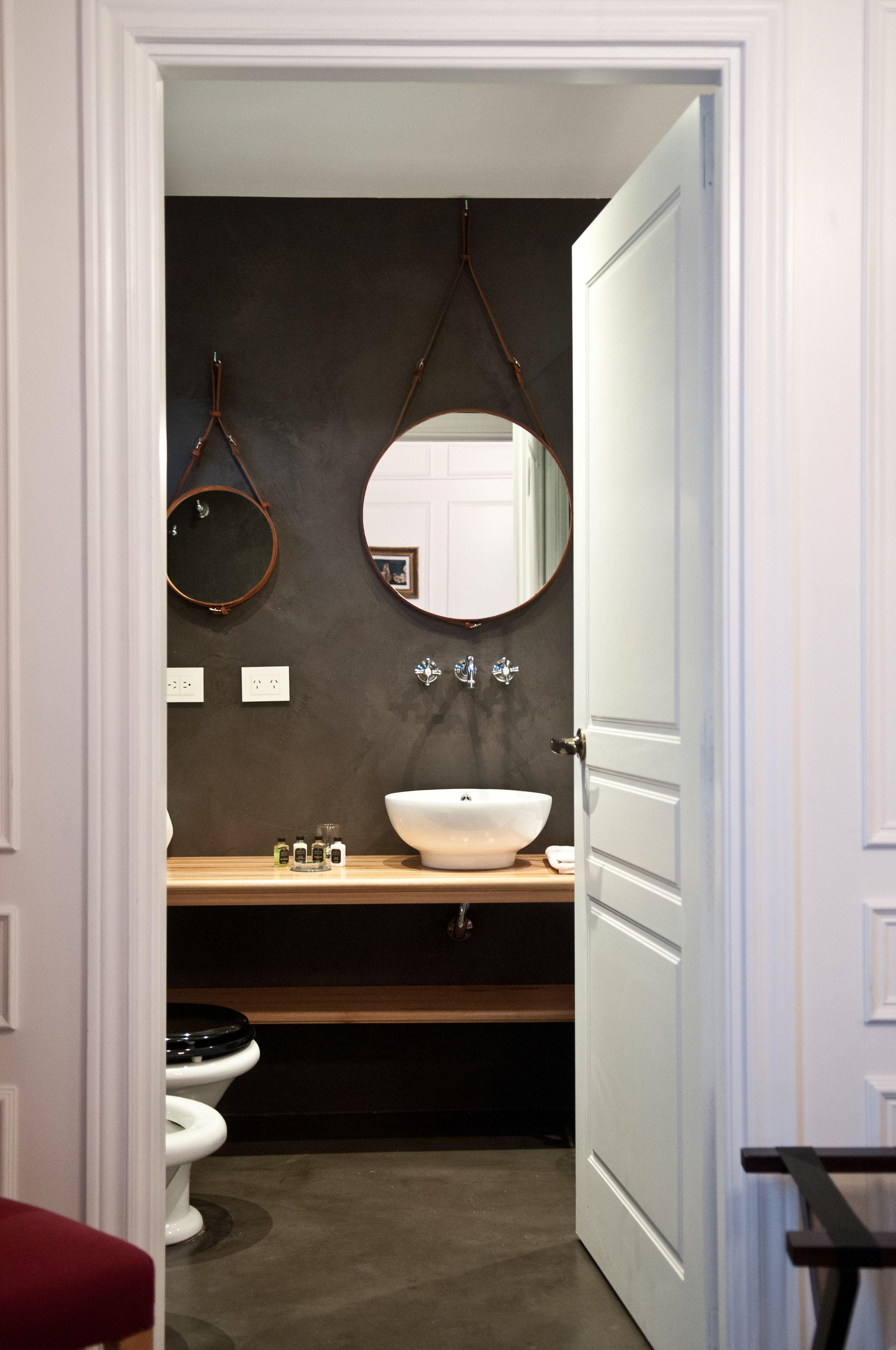 A bathroom with a white sink, a round mirror, and a toilet.