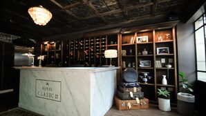A hotel bar area with a marble counter labeled "HOTEL CLASSIC," wooden shelves with various items, and a chandelier. - Hotel Clasico (Buenos Aires)