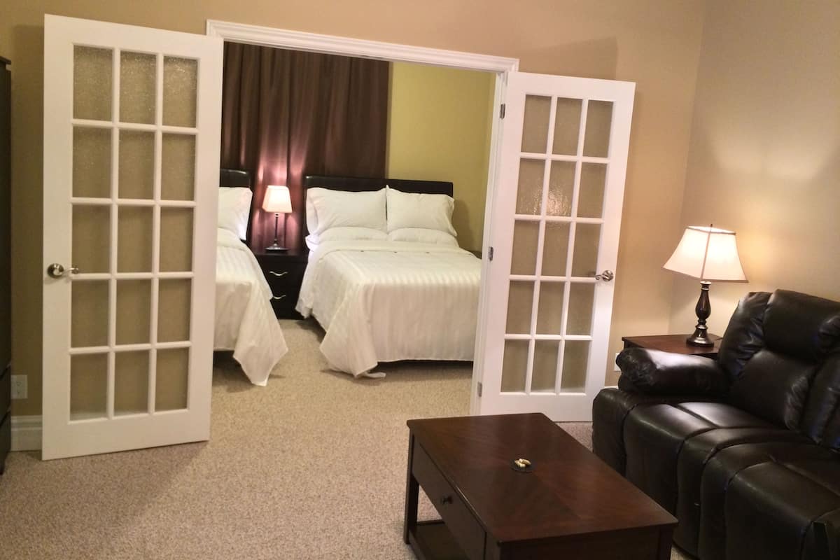 A hotel room with two beds, a sofa, a coffee table, and a lamp.