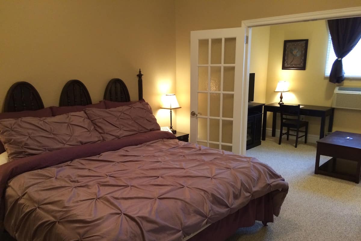 A bedroom with a large bed, a desk, and a chair.
