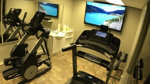 A gym with treadmills, a stationary bike, and a TV displaying a scenic landscape. - Balsam Suites Boutique Inn & Residence (Timmins)
