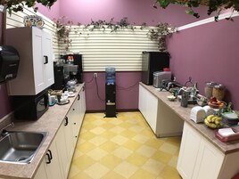 Cocina compacta con microondas, cafetera, dispensador de agua y varios alimentos en la encimera.