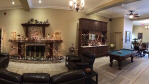 A spacious living room with a fireplace, a pool table, and a library. - Balsam Suites Boutique Inn & Residence (Timmins)