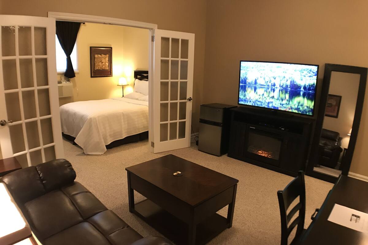 A hotel room with a bed, a television, a fireplace, a sofa, and a coffee table.