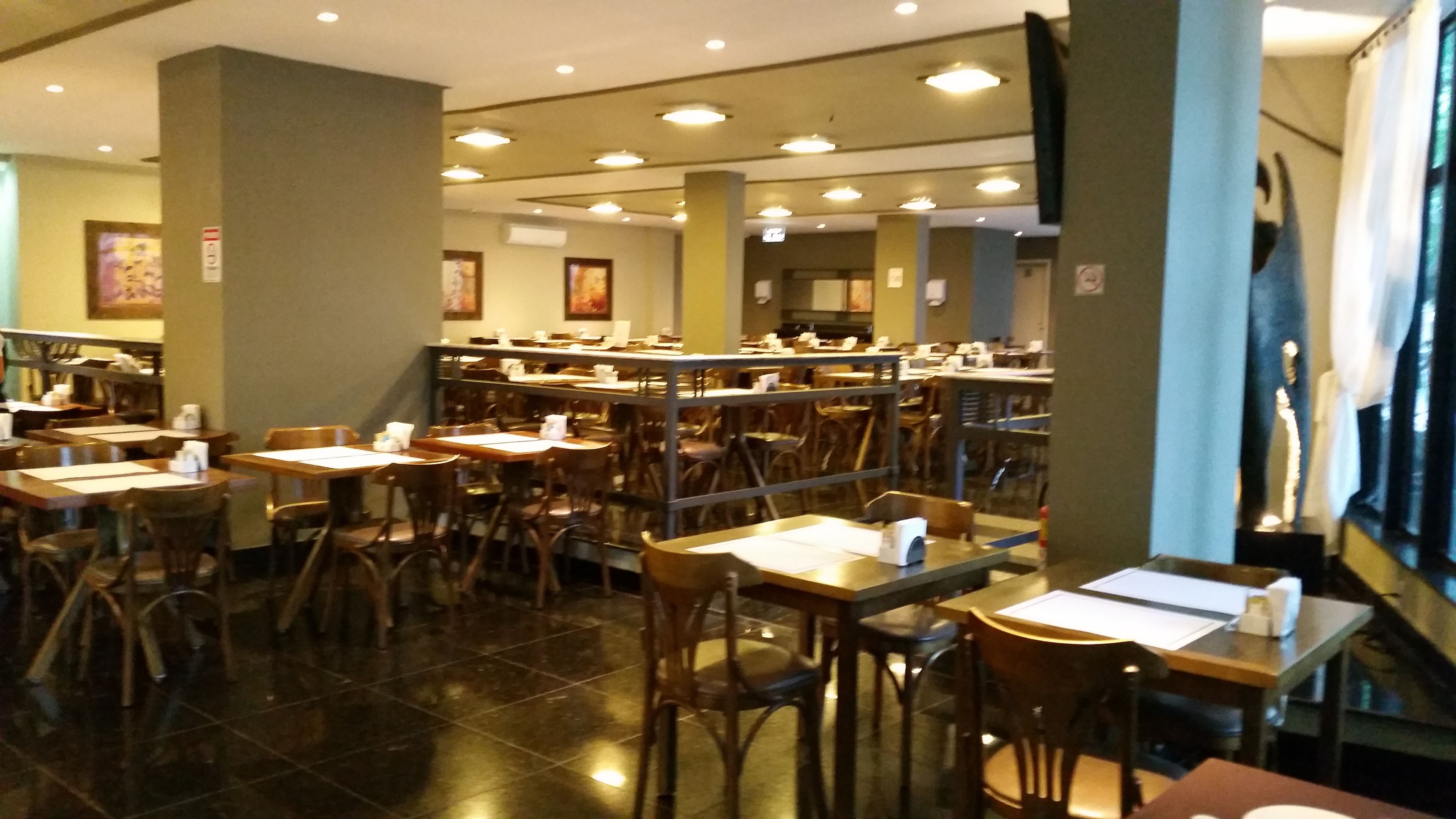 Ein Restaurant mit mehreren Tischen und Stühlen, einem Fliesenboden und Deckenleuchten.