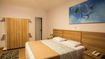 A bedroom with a wooden bed, a nightstand, a telephone, and a painting on the wall.