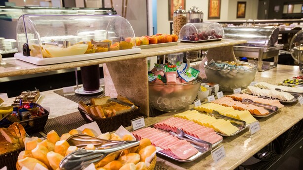 Un bufé con diversos alimentos, incluyendo pan, carnes, quesos y frutas.