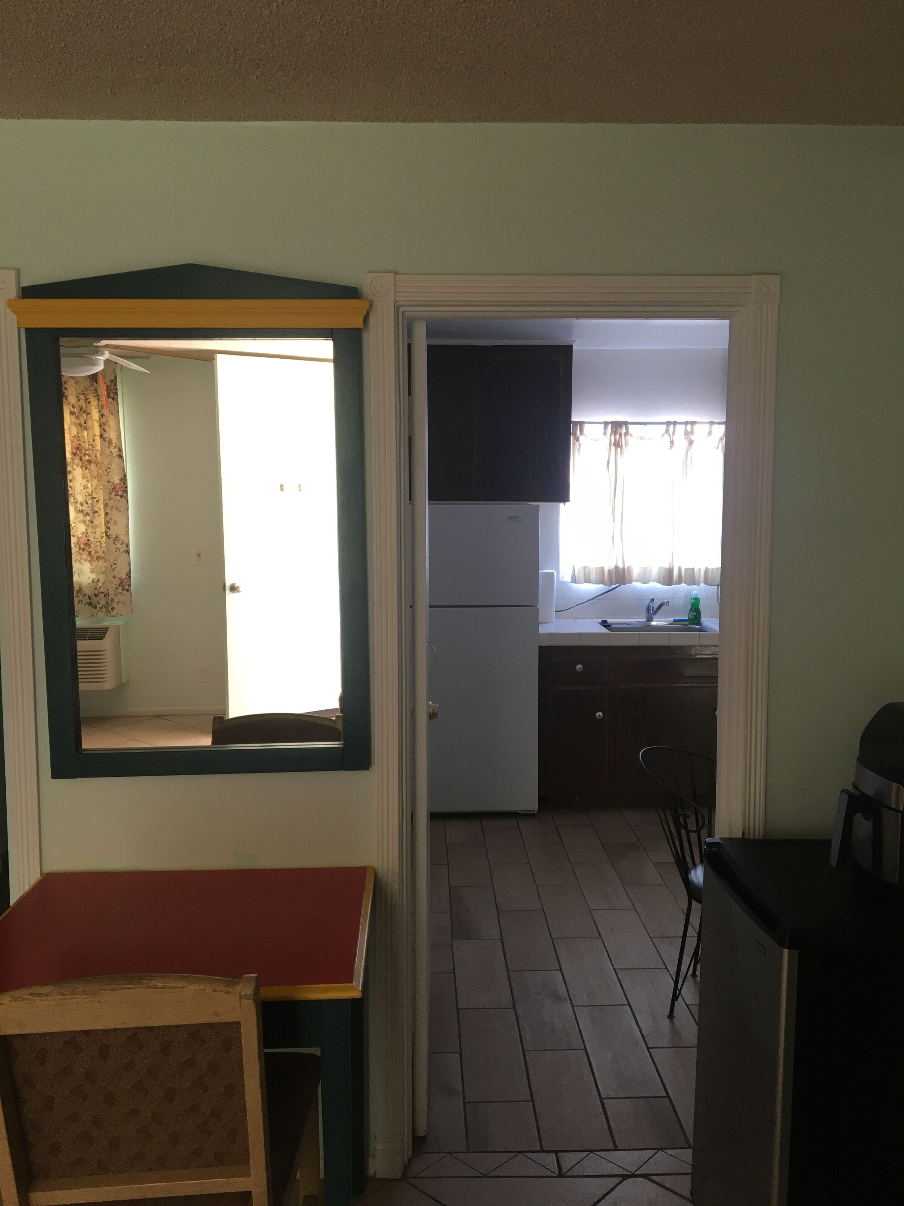 A compact kitchen with a refrigerator, sink, and a small dining area with a table and chairs.