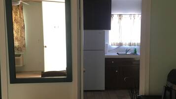 A compact kitchen with a refrigerator, sink, and a small dining area with a table and chairs.