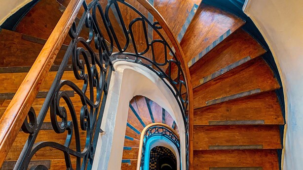 Un escalier en bois avec une rampe incurvée menant à un palier.