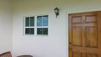 Una habitación con puerta de madera, una ventana con persianas y una pequeña mesa con dos sillas.