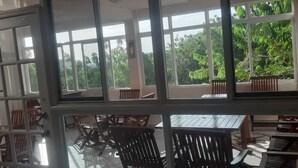 A room with multiple windows, wooden furniture, and a view of greenery outside.