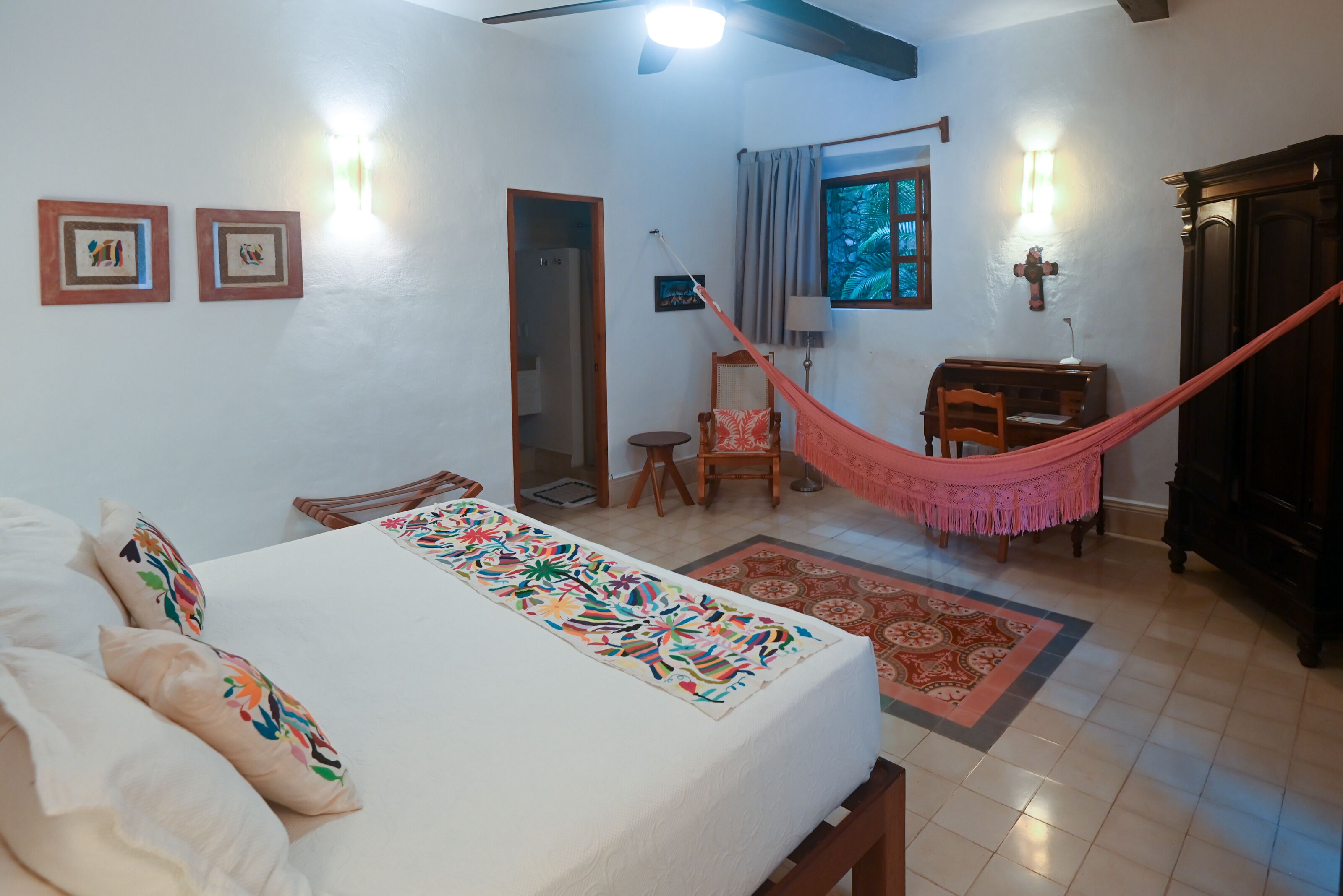 Ein Schlafzimmer mit Bett, einer Hängematte, einem Schreibtisch und einem Sessel.
