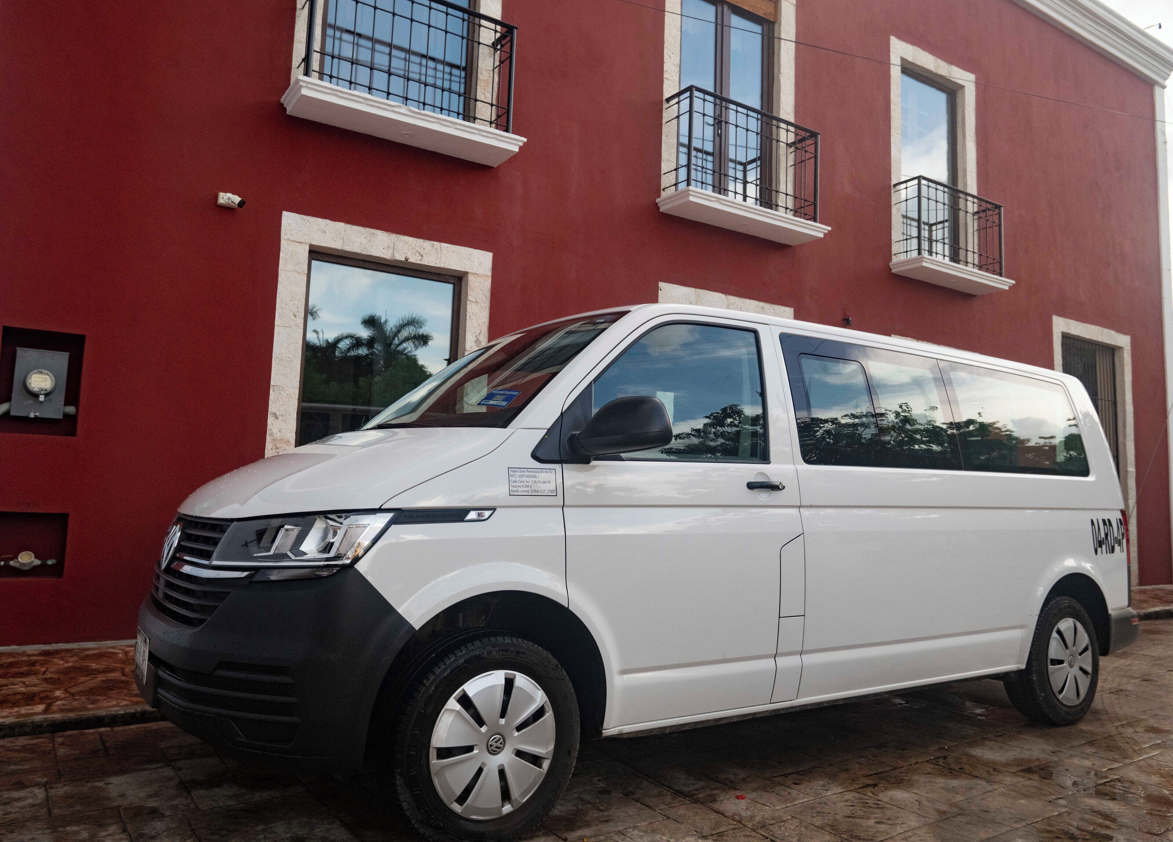 Una camioneta blanca estacionada frente a un edificio rojo con balcones.