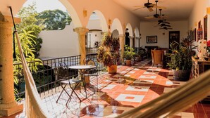 Un patio iluminado por el sol con suelo de baldosas, una hamaca y plantas en macetas.