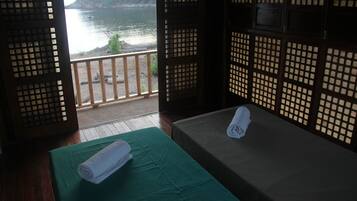 Enjoy a serene view of the surrounding landscape from the comfort of this traditional room, featuring a wooden lattice partition and two beds with green bedspreads.