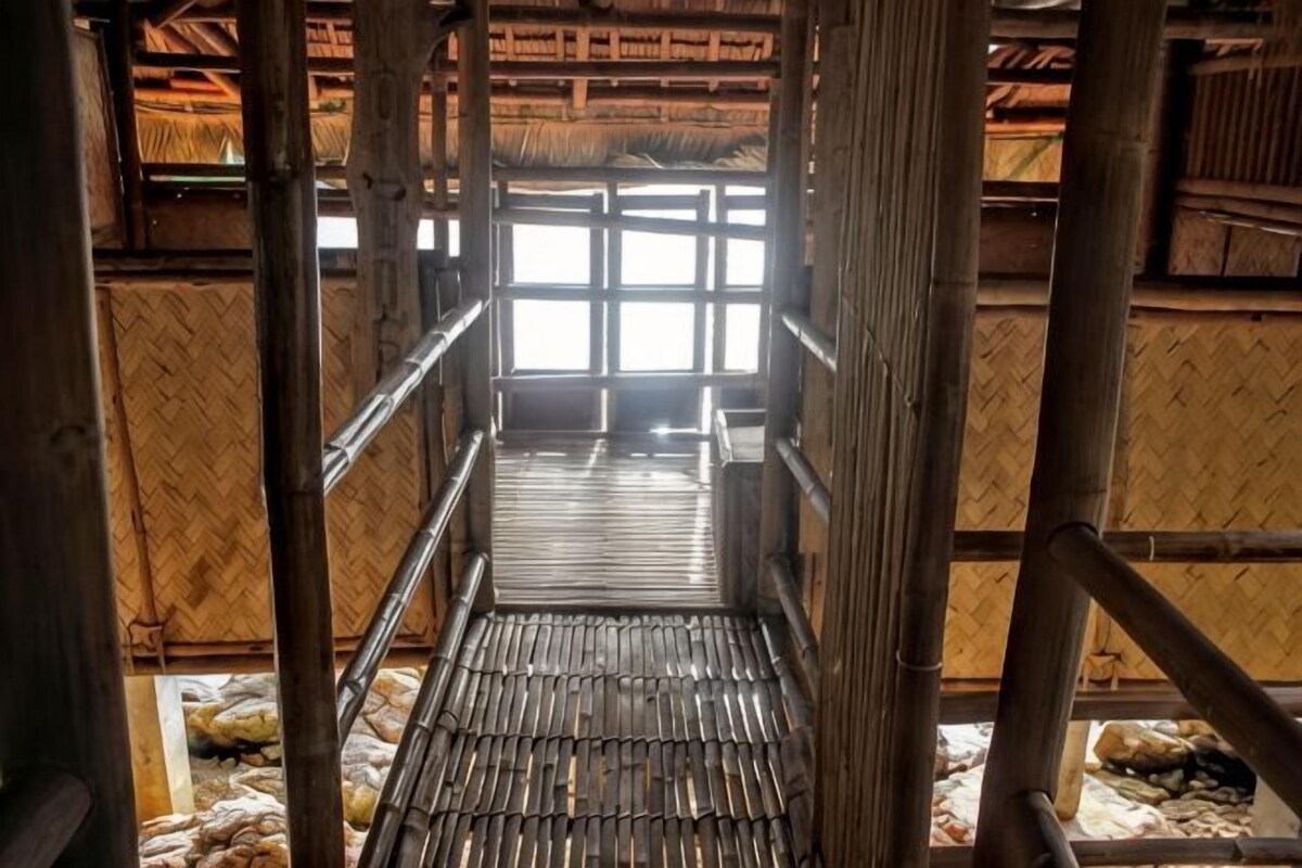 A bamboo structure with a central walkway and a thatched roof.