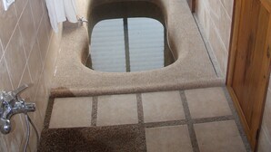A bathroom with a bathtub, a shower, and a window with blinds.