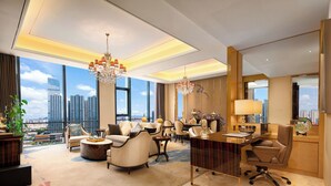 Une chambre d’hôtel spacieuse avec vue sur la ville, un lustre, un bureau et un coin repas.