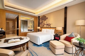 Habitación de hotel con cama, escritorio, silla, sofá, mesa y lámpara.