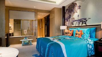 A modern hotel room with a large bed, a desk, and a bathroom visible through a glass partition.
