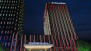 Un hôtel moderne doté d’un éclairage vertical remarquable et d’une enseigne indiquant « WandaVista ».