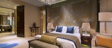 Une chambre d’hôtel avec un grand lit, deux tables de chevet, un banc, un lustre et un mur décoratif.